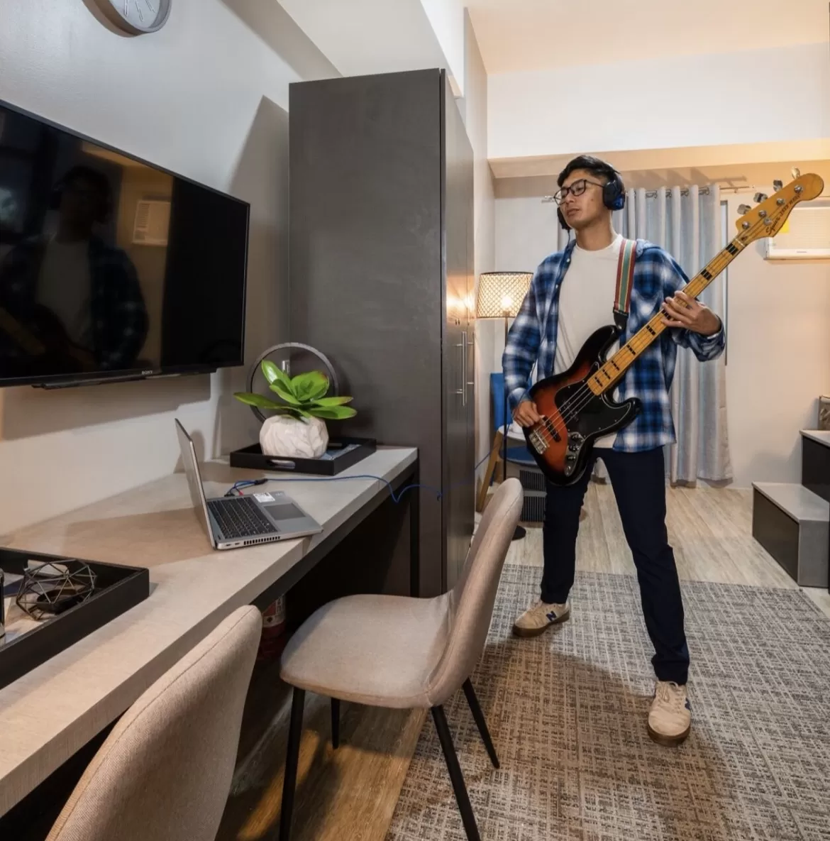 a young musician playing guitar in his condo unit for better mental health