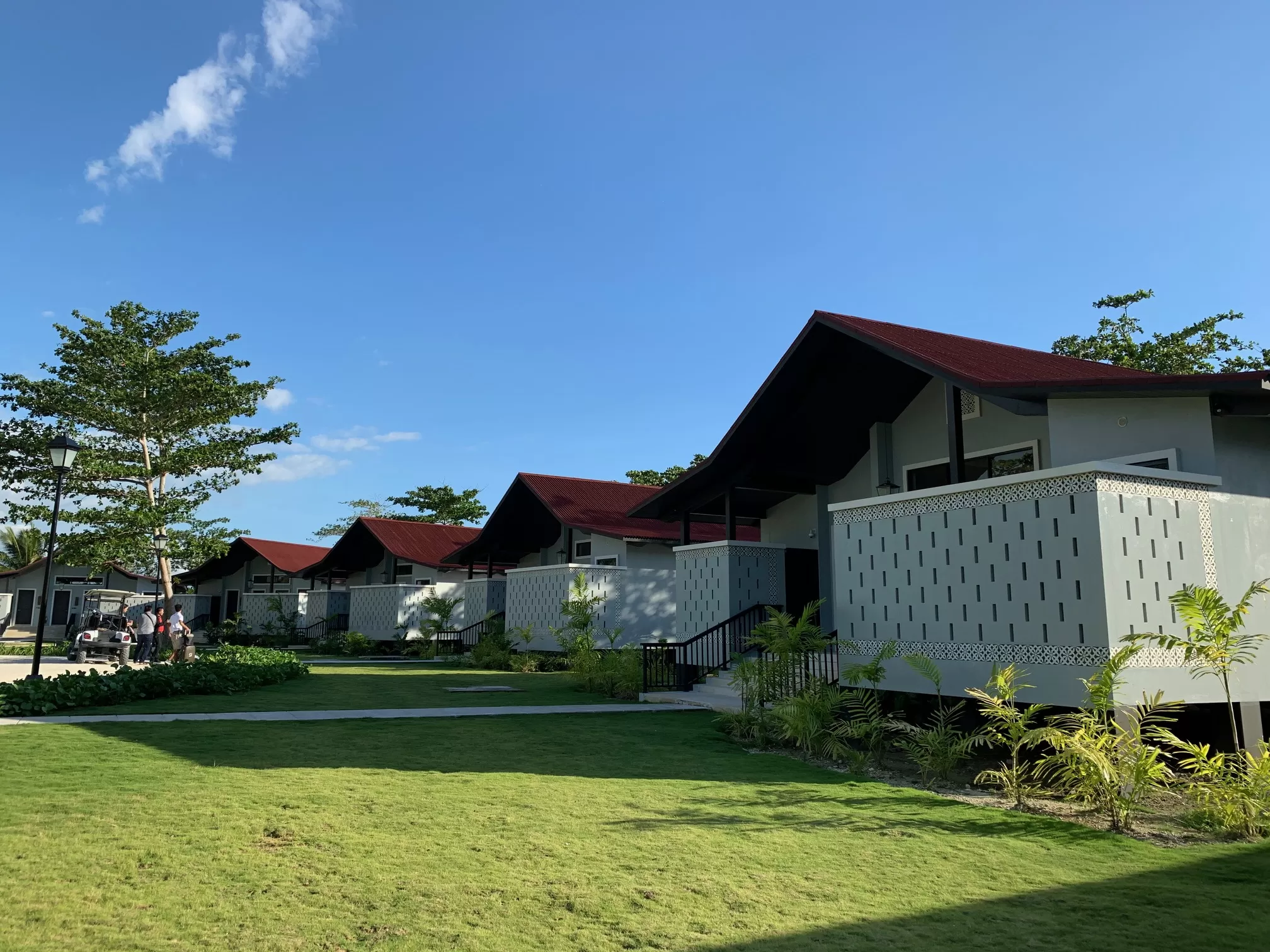 a row of houses with a lawn and trees at dusit thani lubi plantation resort